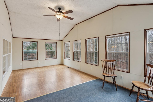 unfurnished room with lofted ceiling, a textured ceiling, light wood-type flooring, ornamental molding, and ceiling fan