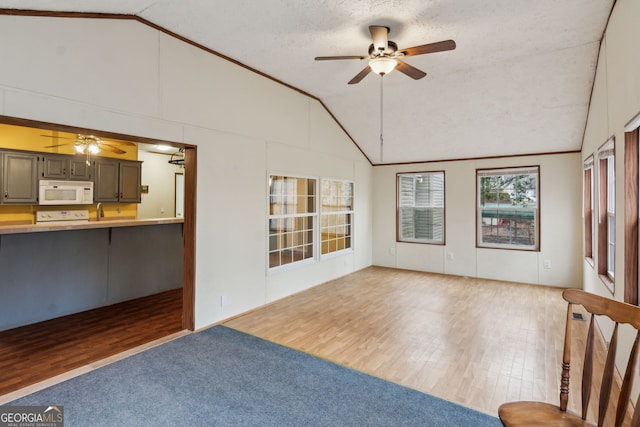 unfurnished living room with crown molding, high vaulted ceiling, a textured ceiling, ceiling fan, and hardwood / wood-style floors