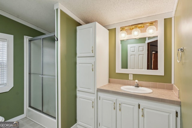 bathroom with an enclosed shower, vanity, and a textured ceiling