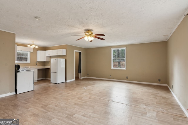 unfurnished living room with ceiling fan with notable chandelier, a textured ceiling, and light wood-type flooring