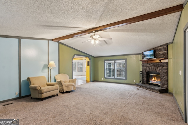 living area with vaulted ceiling with beams, a textured ceiling, carpet floors, ceiling fan, and a fireplace