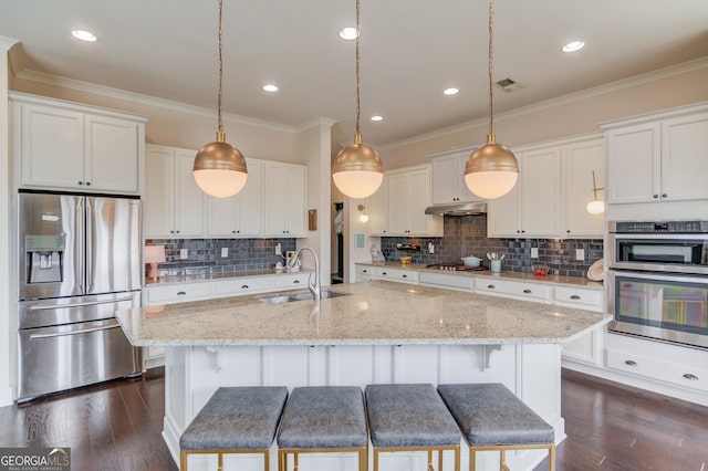 kitchen featuring pendant lighting, sink, appliances with stainless steel finishes, white cabinetry, and an island with sink