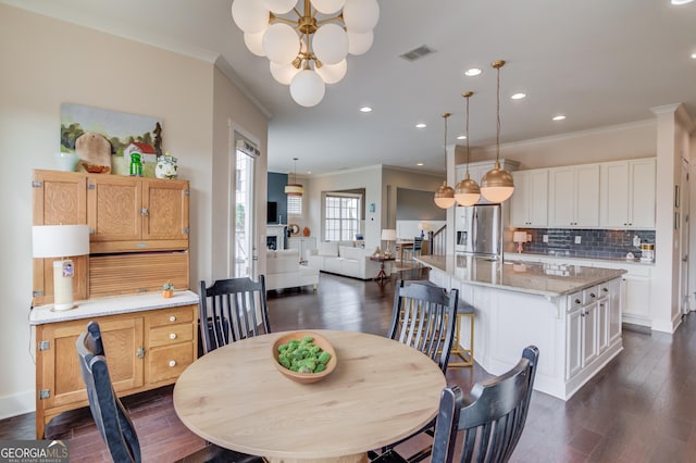 dining space featuring crown molding, dark wood-type flooring, and an inviting chandelier