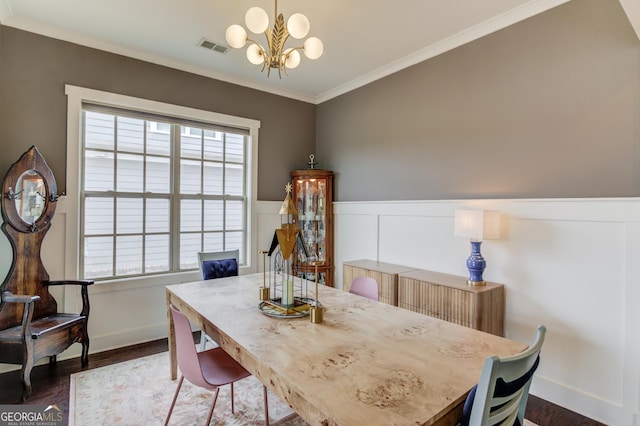 dining area with ornamental molding, dark hardwood / wood-style floors, and an inviting chandelier