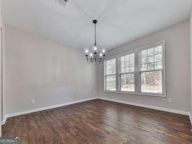 empty room with an inviting chandelier and dark wood-type flooring