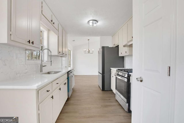 kitchen featuring pendant lighting, tasteful backsplash, white cabinetry, sink, and stainless steel appliances