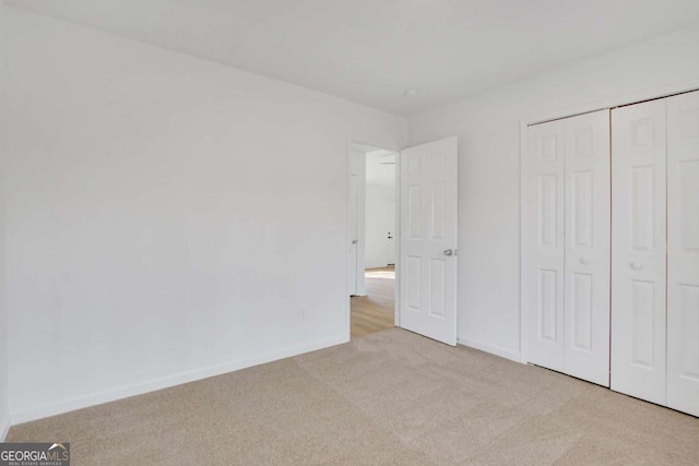 unfurnished bedroom featuring light carpet and a closet