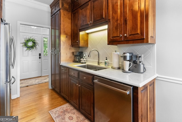 kitchen featuring sink, crown molding, backsplash, stainless steel appliances, and light hardwood / wood-style floors