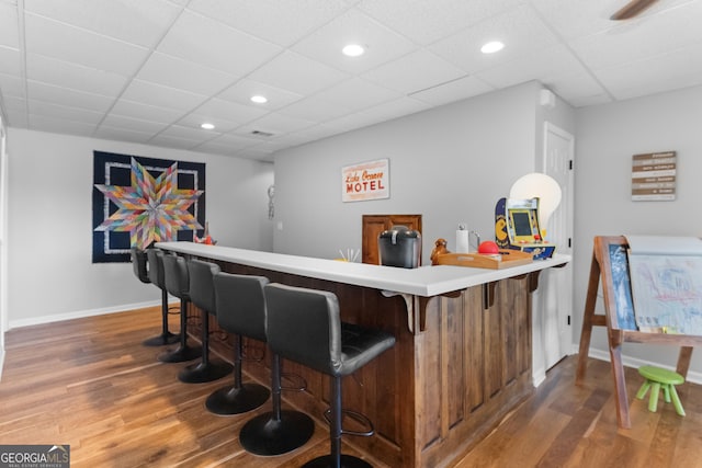 bar with dark wood-type flooring and a paneled ceiling