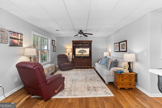 living room featuring ceiling fan, hardwood / wood-style floors, and a drop ceiling