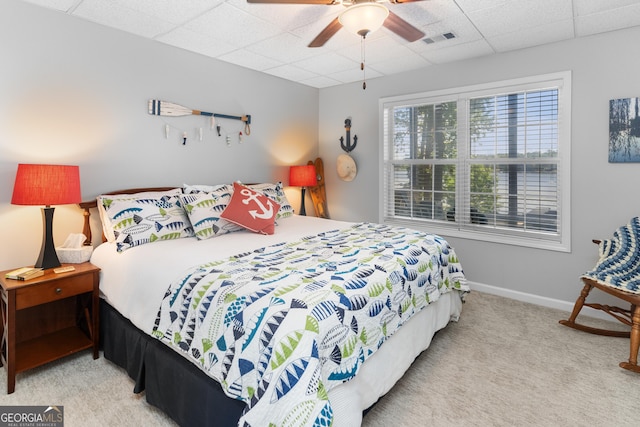 bedroom with a paneled ceiling, light colored carpet, and ceiling fan