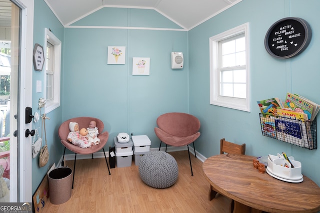 living area featuring crown molding, vaulted ceiling, and light hardwood / wood-style floors