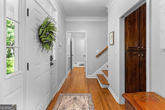 entrance foyer with ornamental molding and light hardwood / wood-style flooring