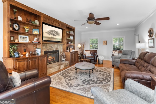 living room featuring crown molding, ceiling fan, a fireplace, and light hardwood / wood-style floors