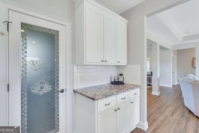 kitchen featuring light stone counters, light hardwood / wood-style flooring, decorative backsplash, and white cabinets