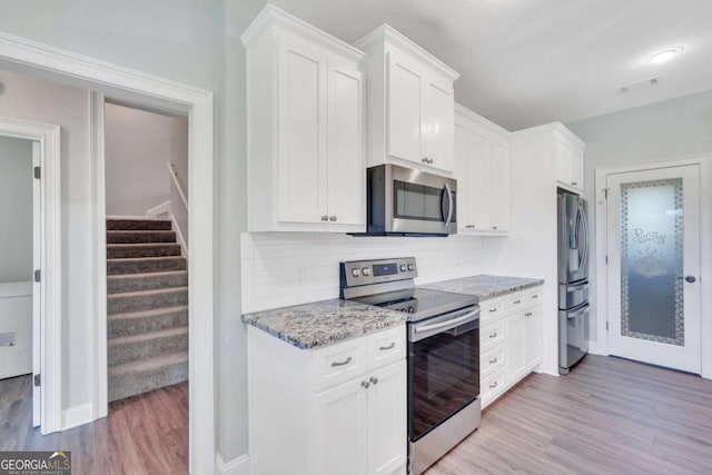 kitchen with white cabinetry, light stone countertops, light hardwood / wood-style flooring, and stainless steel appliances