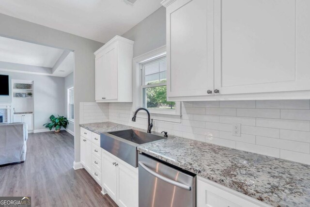 kitchen with sink, white cabinets, decorative backsplash, stainless steel dishwasher, and light stone countertops