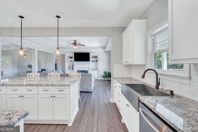 kitchen with pendant lighting, sink, white cabinetry, stainless steel dishwasher, and a raised ceiling