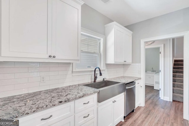 kitchen featuring sink, white cabinetry, dishwasher, light stone countertops, and light hardwood / wood-style floors