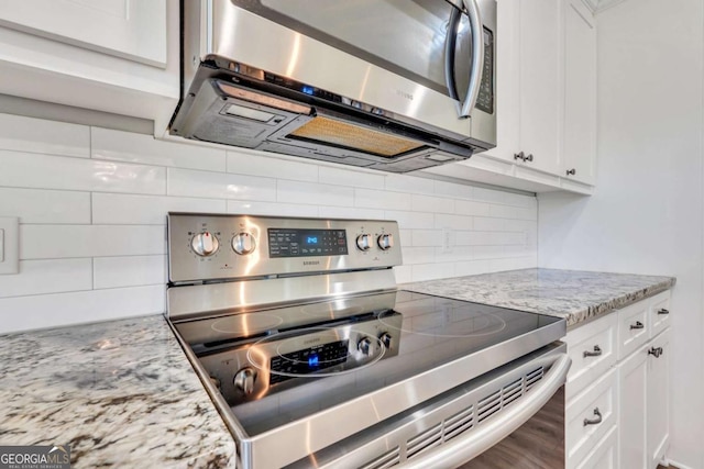 kitchen featuring white cabinetry, tasteful backsplash, light stone countertops, and appliances with stainless steel finishes