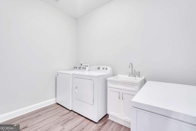 washroom featuring separate washer and dryer, sink, light hardwood / wood-style flooring, and cabinets