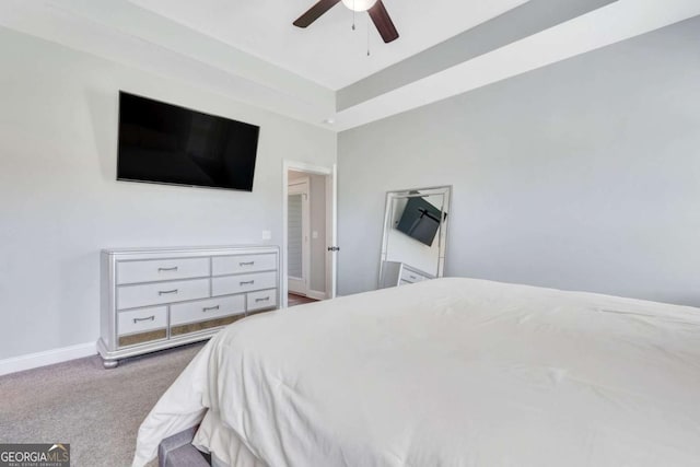 carpeted bedroom featuring ceiling fan and a raised ceiling