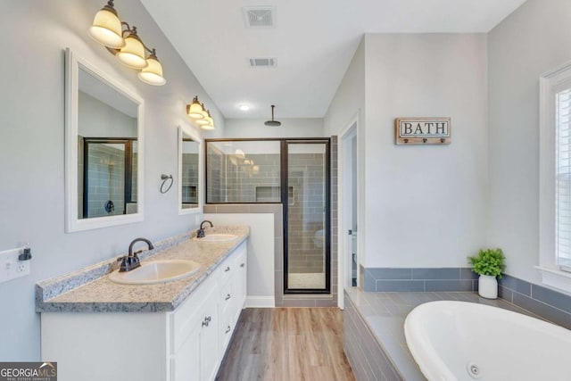 bathroom featuring hardwood / wood-style flooring, shower with separate bathtub, and vanity