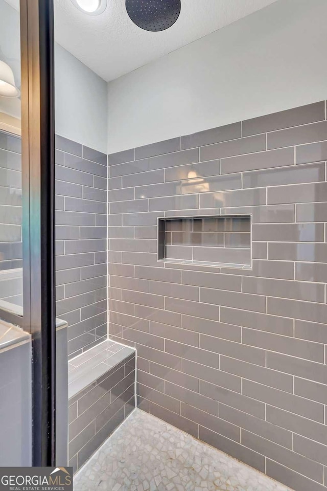 bathroom with tiled shower and a textured ceiling