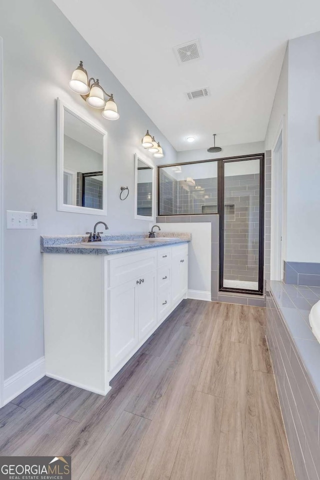 bathroom featuring hardwood / wood-style flooring, shower with separate bathtub, and vanity