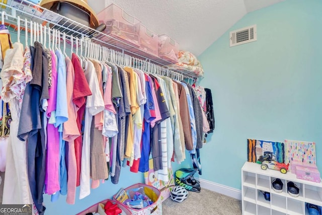 walk in closet with carpet and lofted ceiling