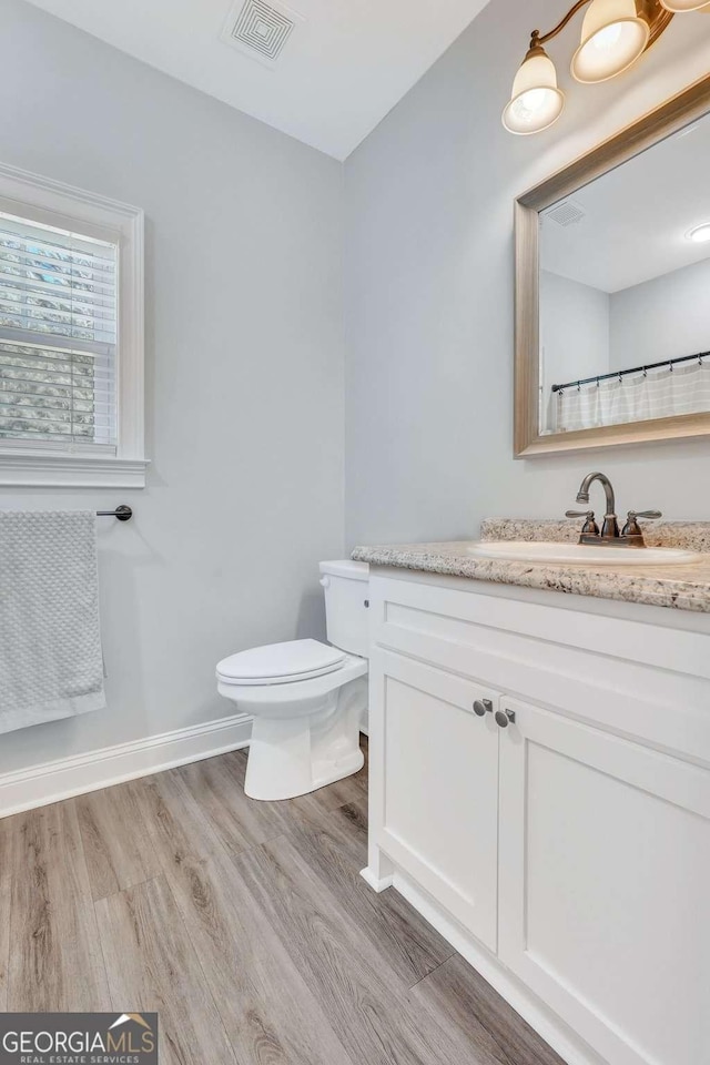 bathroom featuring wood-type flooring, vanity, and toilet