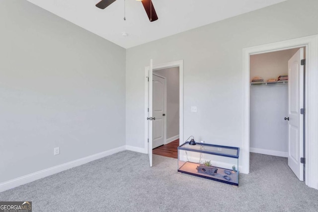 bedroom with a walk in closet, a closet, ceiling fan, and carpet