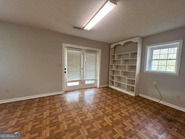 spare room with dark parquet flooring and a textured ceiling