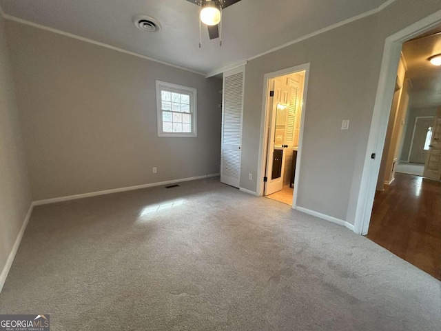 unfurnished bedroom featuring crown molding, light colored carpet, ensuite bathroom, and ceiling fan