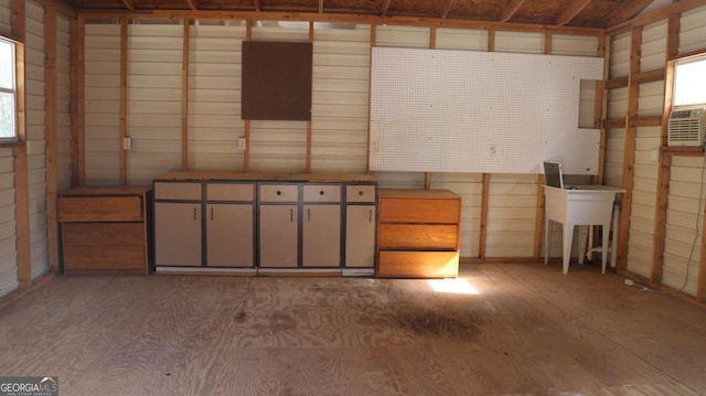 basement featuring cooling unit, sink, and hardwood / wood-style floors