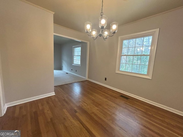 unfurnished dining area featuring dark wood-type flooring, ornamental molding, and a chandelier