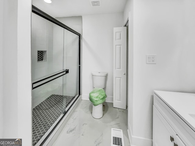 bathroom featuring vanity, toilet, and a shower with shower door