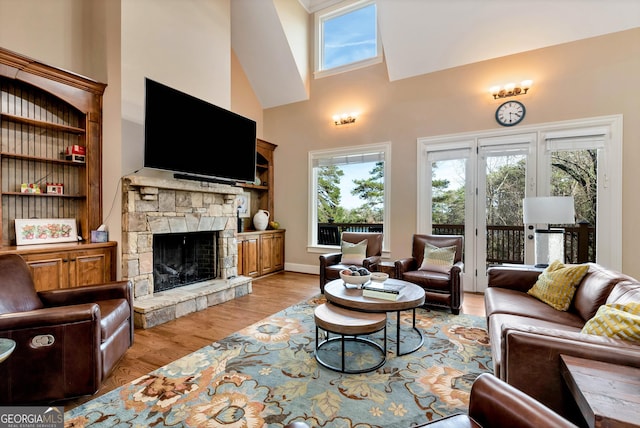 living room featuring a stone fireplace, light hardwood / wood-style floors, and a high ceiling