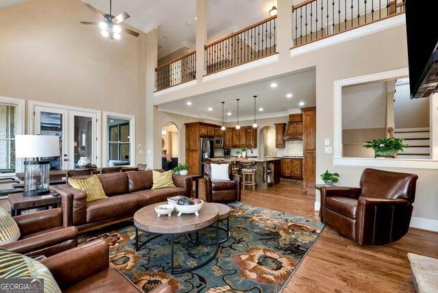 dining room with crown molding, a fireplace, a towering ceiling, and light wood-type flooring