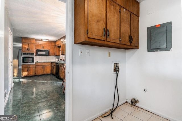 kitchen with tasteful backsplash, stainless steel oven, electric panel, and light tile patterned floors