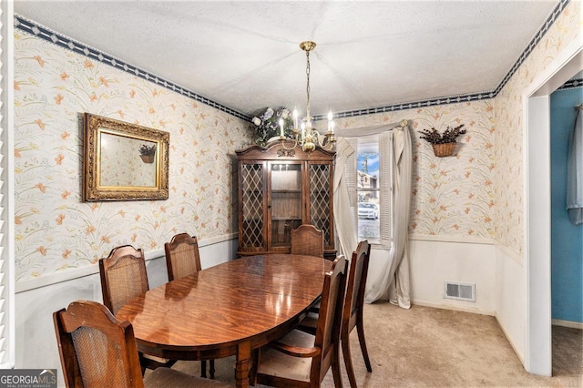 carpeted dining space with a chandelier and a textured ceiling