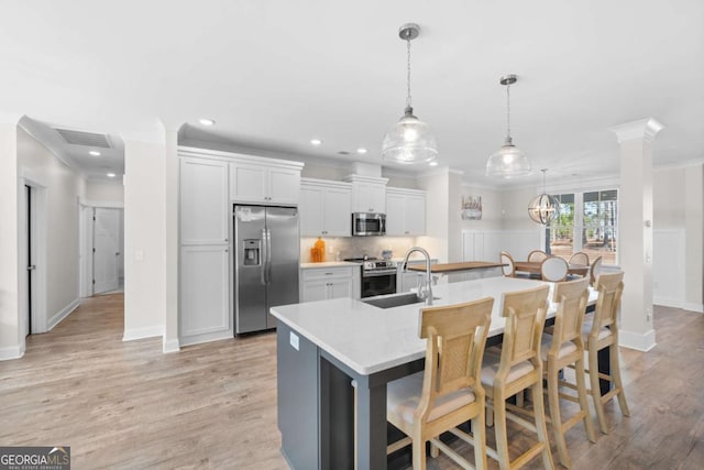 kitchen with sink, a breakfast bar area, appliances with stainless steel finishes, white cabinetry, and an island with sink