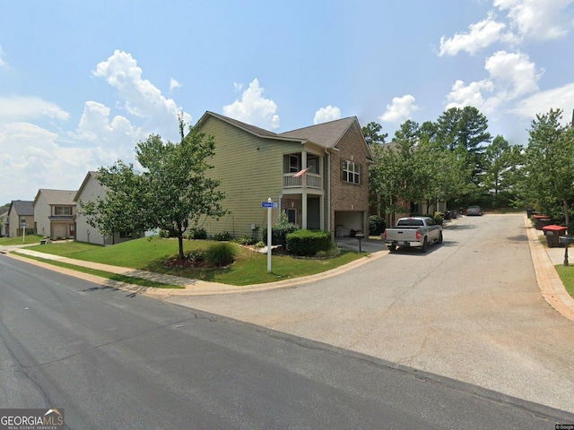 view of front of property featuring driveway, an attached garage, a residential view, and a front yard