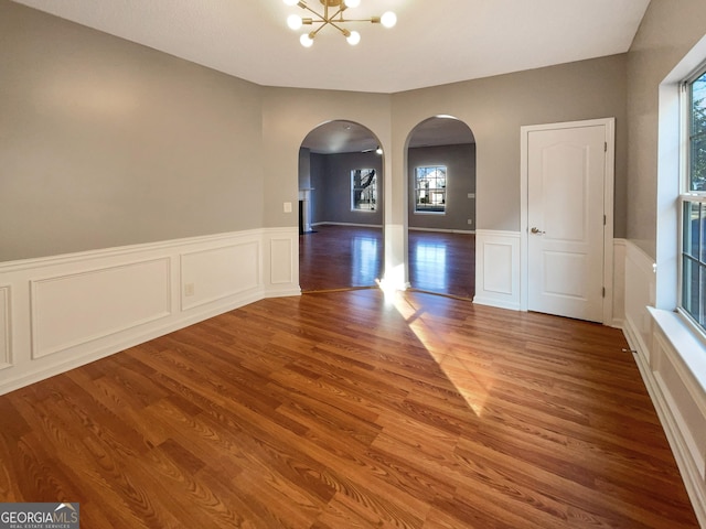 unfurnished room featuring hardwood / wood-style flooring, an inviting chandelier, and a wealth of natural light