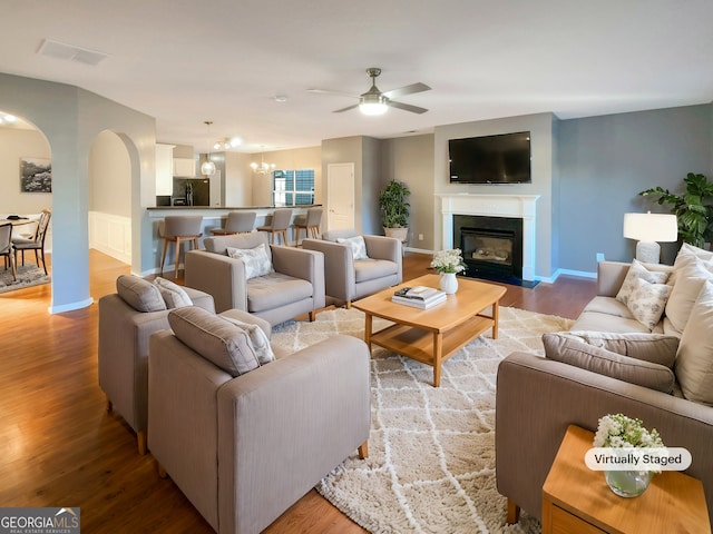 living room with hardwood / wood-style floors and ceiling fan with notable chandelier