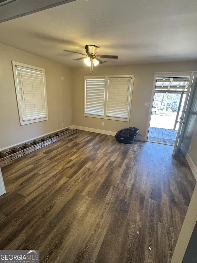 interior space featuring ceiling fan, dark wood-type flooring, and a textured ceiling