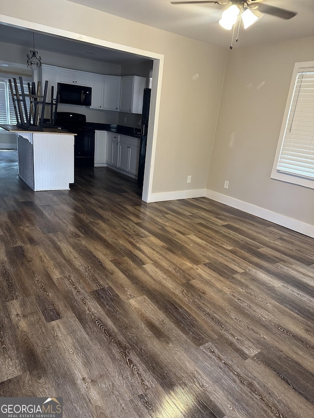 kitchen with dark wood-type flooring, black appliances, ceiling fan, decorative light fixtures, and a kitchen island