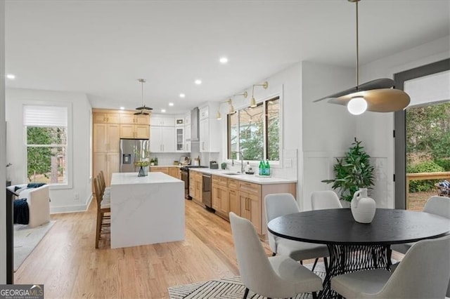 kitchen featuring stainless steel appliances, a healthy amount of sunlight, a kitchen island, and a sink