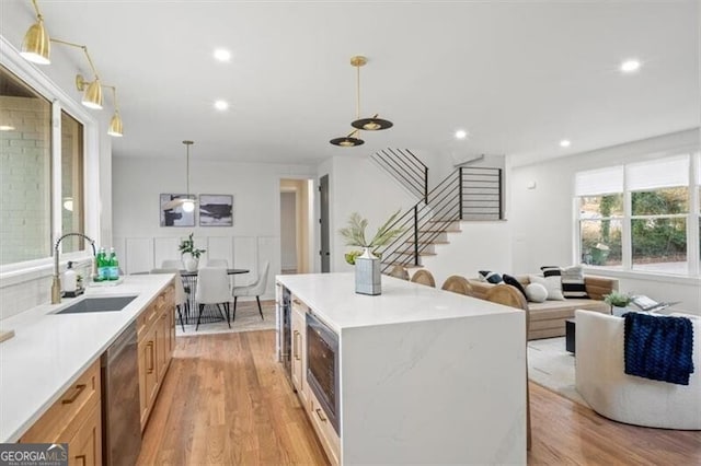 kitchen featuring stainless steel appliances, light wood finished floors, a sink, and light countertops