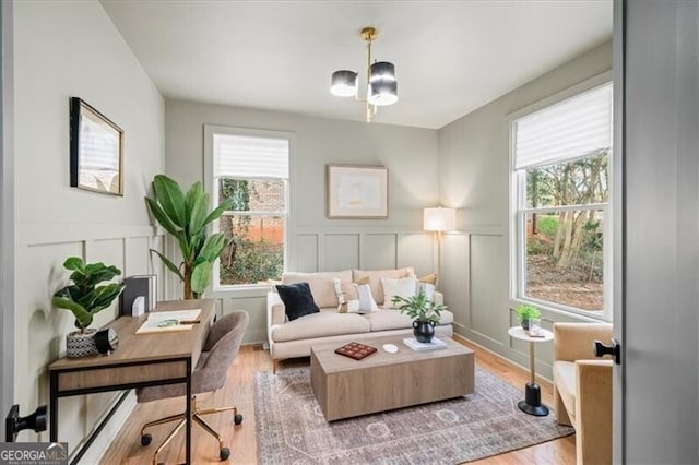 sitting room with plenty of natural light, light wood-style flooring, and a decorative wall